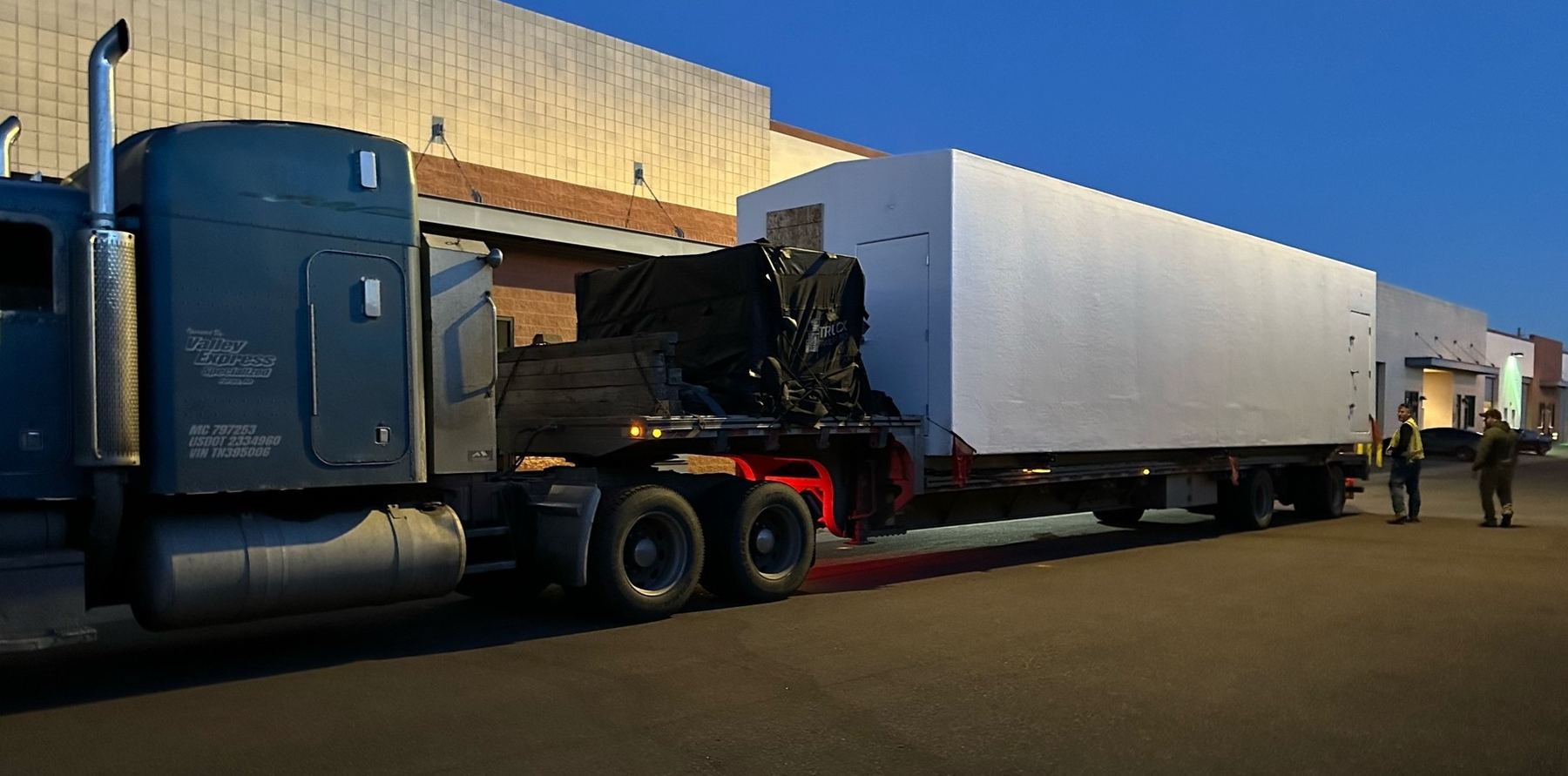 An M3 production module on a flatbed truck at dusk